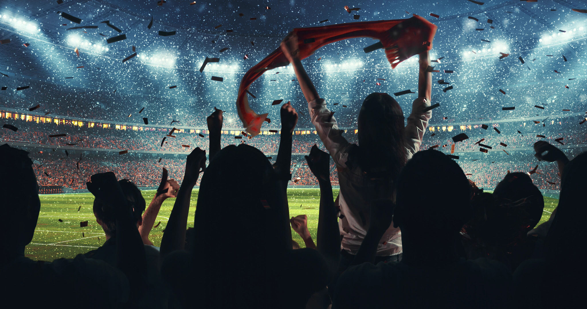 Inside the illuminated stadium where confetti is swirling, many people are excited, waving towels and raising their hands.